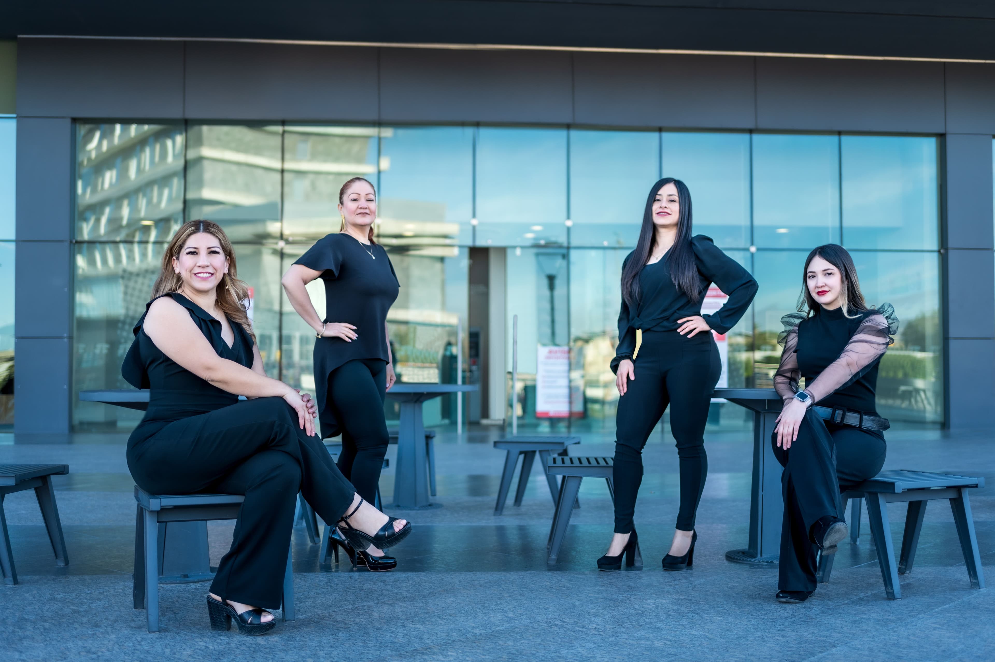 Four Latina professionals gathered outside a business building